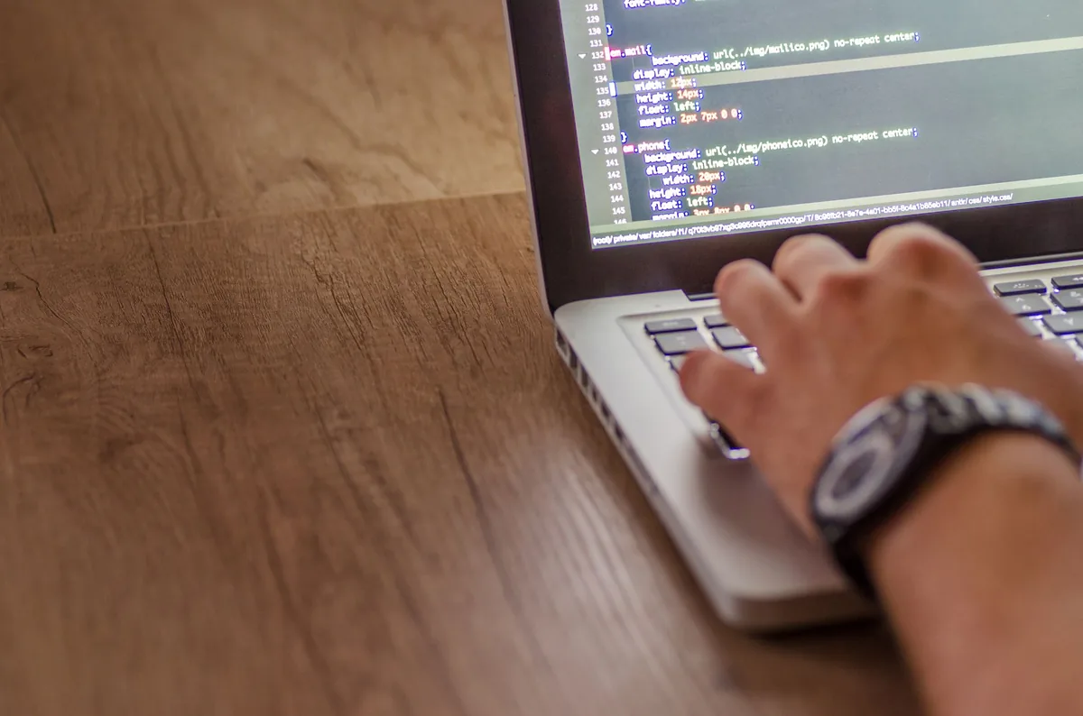 Mãos digitando código em notebook com editor aberto, ilustrando auditoria do uso de modelos da OpenAI