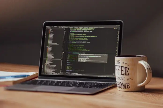Notebook com editor de código aberto sobre mesa de madeira ao lado de caneca de café, ilustrando rotina de migração de modelos no Cursor